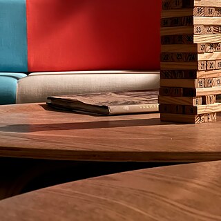 Hölzerne Bauteile, die zu einem Turm aufgebaut sind, stehen auf einem Couchtisch.