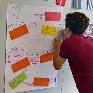 Jugendlicher malt ein Plakat.