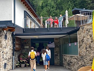 Jugendliche vor dem Alpincenter, auf der Terrasse spielt jemand Gitarre.