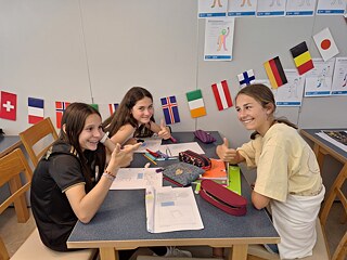 Jugendliche sitzen um einen Tisch, auf dem Arbeitsblätter liegen.