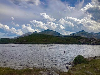 Jugendliche schwimmen in einem See in den Bergen.