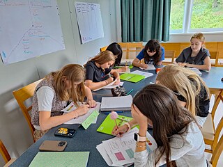 Jugendliche sitzen an Tischen und arbeiten konzentriert.