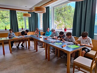 Jugendliche sitzen an in U-Form aufgestellten Tischen in einem Klassenzimmer.