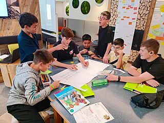 Jugendlicher sitzen um einen Tisch und diskutieren miteinander.