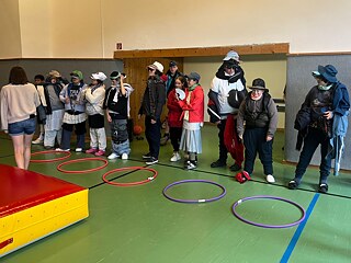 Jugendliche sind sehr dick verkleidet und stehen aufgereiht in einer Sporthalle.