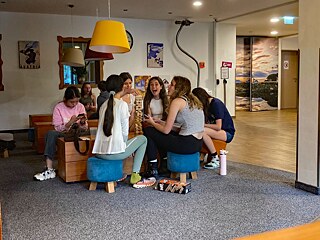 Jugendliche sitzen um einen Couchtisch und spielen ein Geschicklichkeitsspiel mit hölzernen Bauteilen.