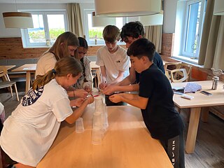 Jugendliche stehen um einen Tisch und spielen.