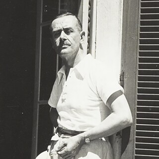 Ein Mann in Sommerkleidung lehnt an der offenen Tür eines Hauses