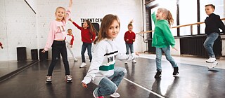 Kinder tanzen in einem Tanzsaal.
