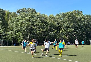 Zwei Fußballteams spielen gegeneinander. Ein Spieler holt zum Schuss aus.