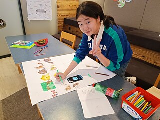 Jugendliche malt ein Plakat.