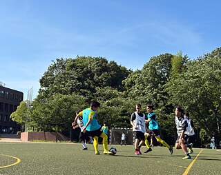 Die Schüler sind am Fußball spielen und kämpfen um den Ballbesitz.