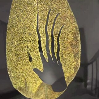 A large gold leaf with a cut out of a hand creating rips in it