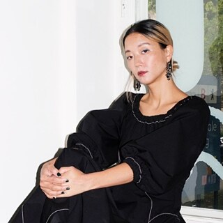 Ein Bild von Christine, die auf einem Fenstersims sitzt und schwarz-weiß gekleidet ist