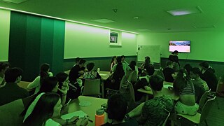 Jugendliche in einem Raum blicken auf einen Bildschirm.