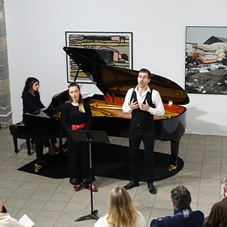 Un homme et une femme chantent devant un piano