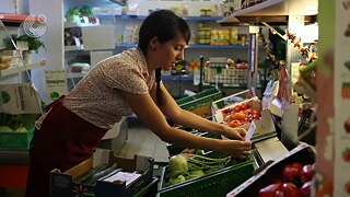 Die junge Frau Nevin sortiert Gemüse ein in einem Laden.