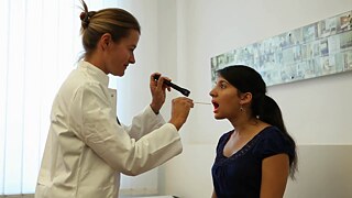 Die junge Frau Nevin hat ihren Mund geöffnet, eine Ärztin leuchtet mit einer Lampe in ihren Mund.