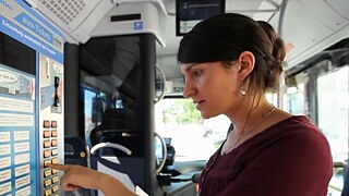 Die junge Frau Nevin steht an einem Fahrkartenautomaten im Bus