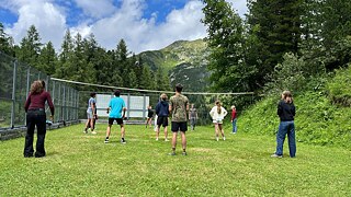 Jugendliche spielen Volleyball auf einer Wiese.