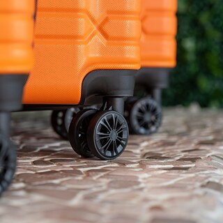 Ein orangefarbener Rollkoffer auf einem Gehweg