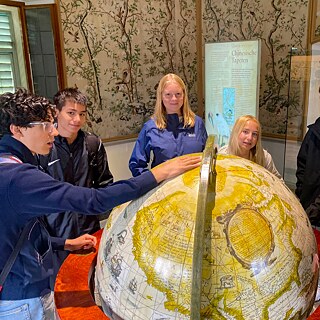 Jugendliche stehen um einen großen Globus im Museum Hellbrunn.