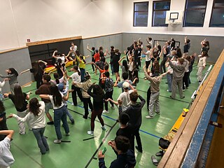 Jugendliche tanzen in einer Sporthalle.