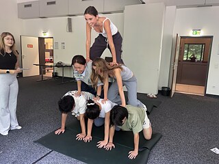 Jugendliche bilden beim Acro Yoga eine Pyramide.