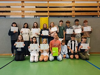 Jugendliche präsentieren stolz ihre Teilnahmebescheinigungen und Zertifikate.