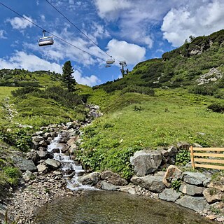 Berglandschaft, ein Bach und eine Seilbahn