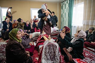 The Gaparov family performing the “Beshik Toi” ceremony, a Central Asian tradition celebrating the placing of a baby in the cradle, in their newly-built home in Maksat village, Kyrgyzstan.