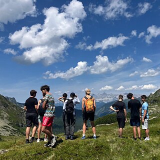 Jugendliche blicken auf die Berglandschaft.