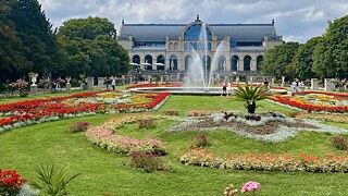 Eine Parkanlage und ein großes Gewächshaus im Hintergrund.