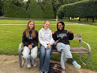 Drei Jugendliche sitzen auf einer Bank im Schlosspark Hellbrunn