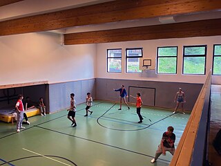 Jugendliche spielen in einer Sporthalle.