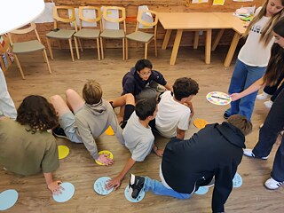 Jugendliche spielen Twister im Unterricht.