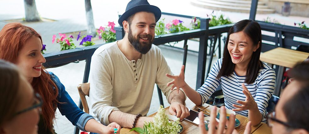 Mladí přátelé sedí v kavárně a diskutují.