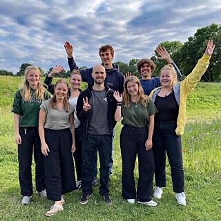 Eine kleine Gruppe junger Menschen grüßt in die Kamera.