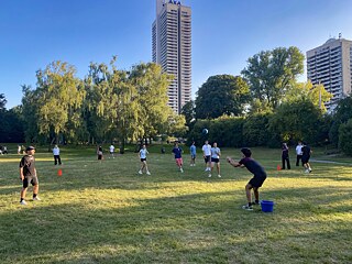 Jugendliche spielen Ball auf einer Wiese.