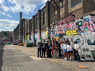 Jugendliche vor einer mit Graffiti dekorierten Ziegelwand