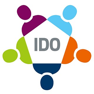 Logo-ul IDO. În centru se află un pentagon stilizat de culoare gri cu inscripția „IDO”. În jurul pentagonului sunt cinci figuri umane stilizate și colorate – în mov, albastru deschis, portocaliu, albastru închis și verde – care se țin de mâini formând un cerc.