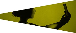 Person macht ein Selfie mit dem Smartphone, in gelblichem Ton, als Symbol für die Bedeutung von Medienkompetenz im digitalen Zeitalter.