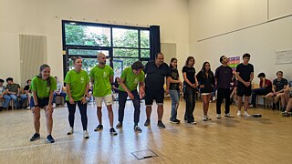 Junge Menschen stehen aufgereiht in einer Sporthalle.