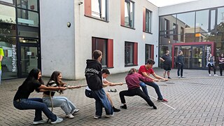 Junge Menschen beim Tauziehen auf einem gepflasterten Hof