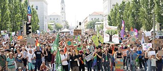 Eine Demonstration von Fridays for Future in München. Man sieht viele junge Menschen, Flaggen und Demoschilder. 