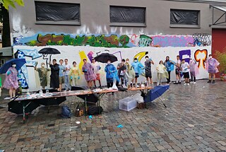 Jugendliche vor einer mit Graffiti besprühten Wand.