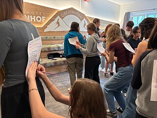 Jugendliche schreiben auf Zettel, die andere auf dem Rücken tragen.