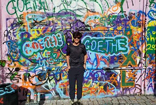 Ein Jugendlicher vor einer mit Graffiti besprühten Wand.