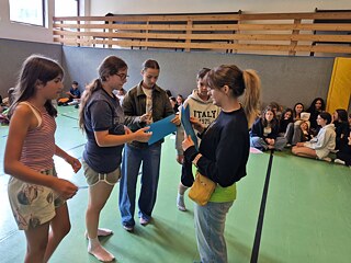 Jugendliche in einer Sporthalle empfangen Urkunden.