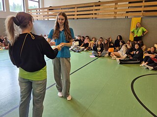 Jugendliche in einer Sporthalle empfangen Urkunden.